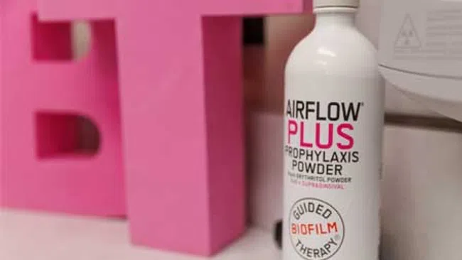 Bottle of AIRFLOW PLUS Prophylaxis Powder for dental biofilm therapy with pink letters and EMS logo.