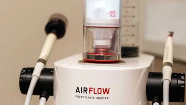 Close-up of AIRFLOW Prophylaxis Master dental equipment with EMS branding and attached handpieces.