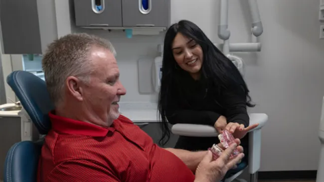 Dental professional explaining dentures to a male patient in a dental office setting.