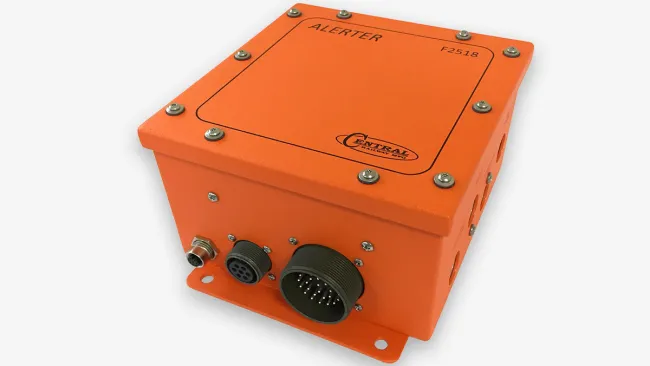 Orange industrial alert device box with multiple connectors and labeled ALERTER on top, isolated on white.