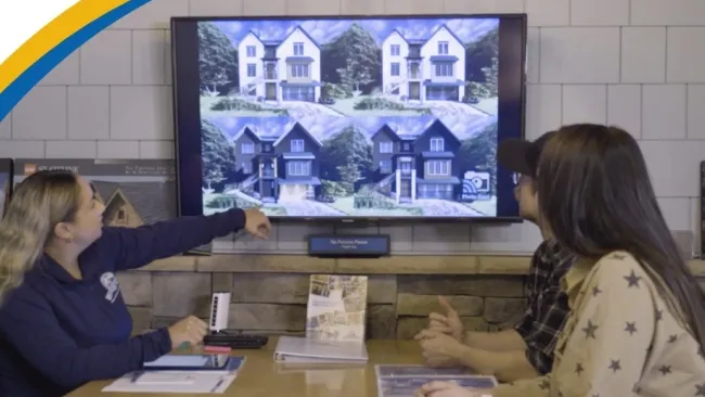 a couple of women sitting at a table looking at a large screen