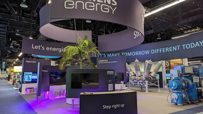 Siemens Energy booth with modern displays, purple lighting, and energy solutions at a trade show.
