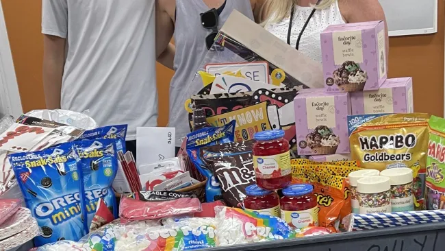 a group of people standing behind a table with food and drinks