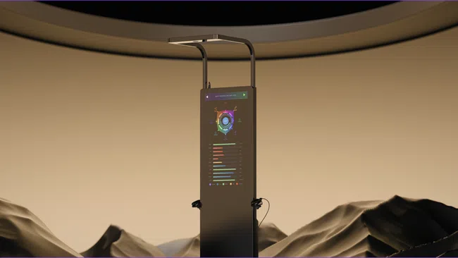 Tall digital kiosk with colorful data charts stands in desert landscape under a curved ceiling structure.