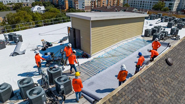 Mattco Roofing and Construction crew installing TPO single-ply roofing membrane on commercial flat roof in Austin Texas