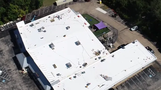 Aerial drone view of completed TPO flat roof installation on commercial building in Texas by Mattco Roofing and Construction