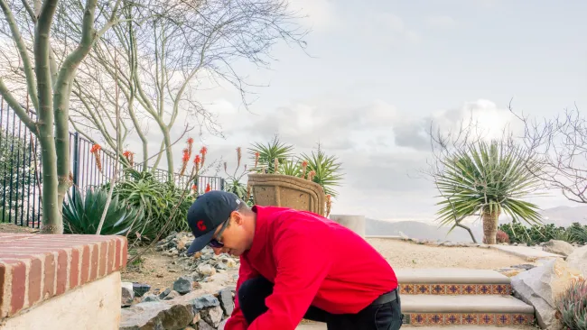 a man squatting down next to a trash can