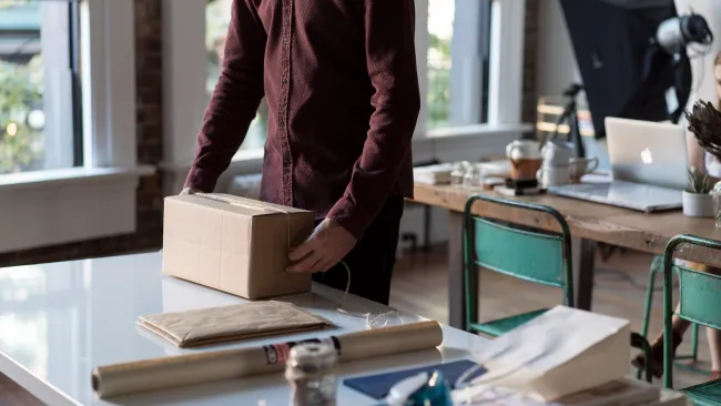 a person standing behind a table with a box and a laptop