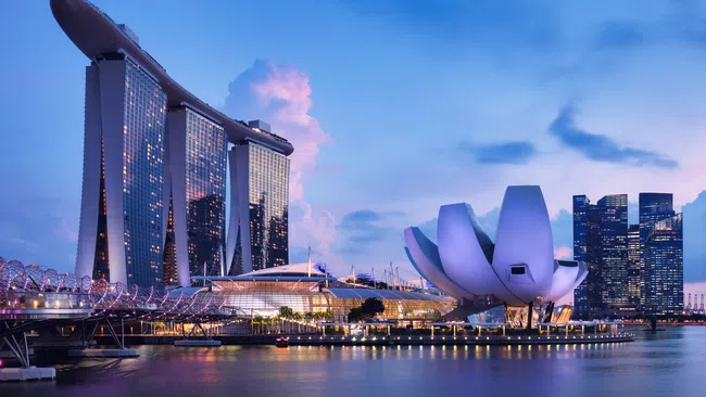 Marina Bay Sands and ArtScience Museum illuminated at dusk along Singapore waterfront with calm water reflections