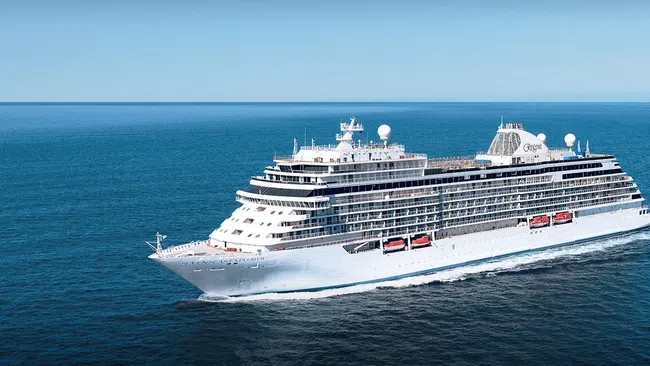 Large white cruise ship sailing on calm blue ocean under clear sky