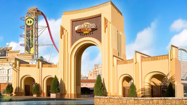 Universal Studios theme park entrance with iconic arch, roller coaster, and clear blue sky on a sunny day