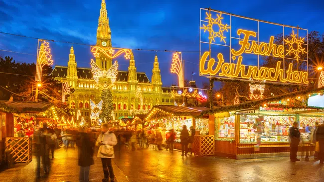 Vienna Christmas market at night with festive lights and illuminated Rathaus building in background