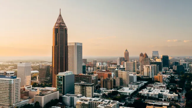 Aerial view of Atlanta skyline at sunset with tall buildings and clear sky in warm light.