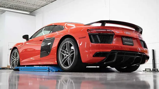 Red Audi R8 sports car in a garage with reflective polished floor and white walls