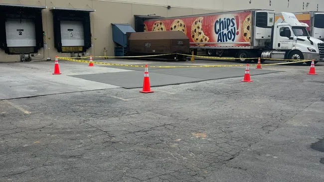 Delivery trucks parked outside a warehouse with colorful Chips Ahoy! branding and traffic cones visible.