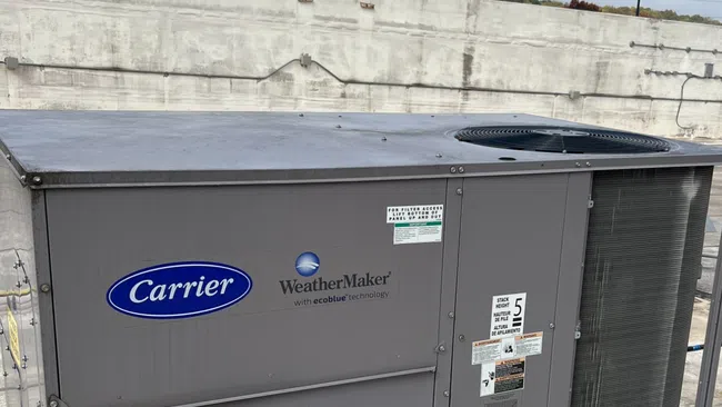 Carrier WeatherMaker rooftop HVAC unit with ecoblue technology installed on a concrete rooftop.