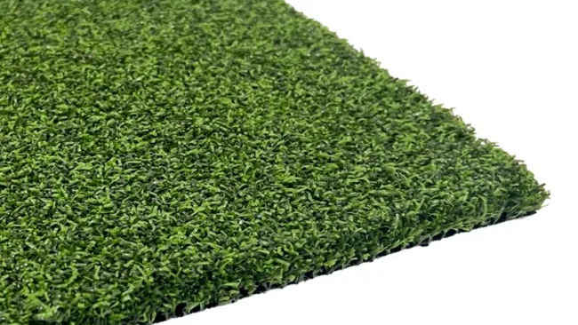 Close-up view of a green artificial grass mat with dense and even texture on a white background.