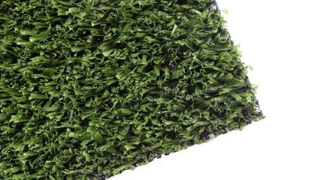 Close-up of a green artificial turf mat with textured plastic grass blades on white background