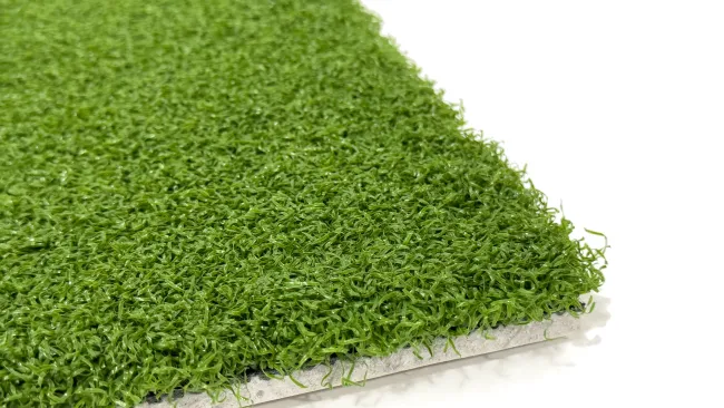 Close-up view of realistic synthetic grass texture on a white background, highlighting vibrant green fibers.