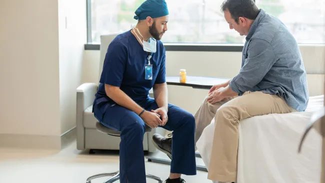 Four healthcare professionals engaging and smiling in a bright, modern medical environment.