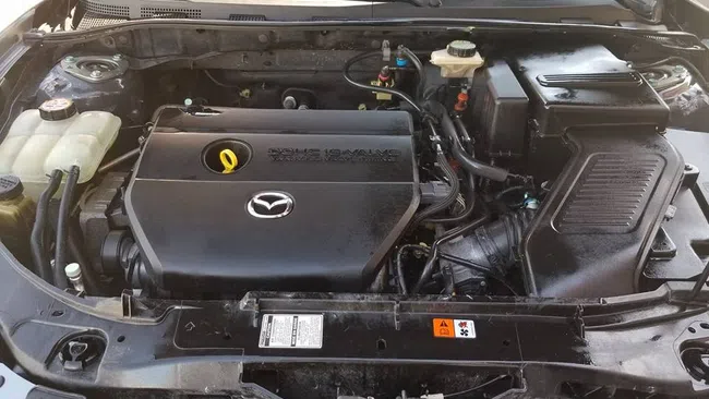 Open hood view of a Mazda car engine showcasing the clean engine cover and surrounding components.