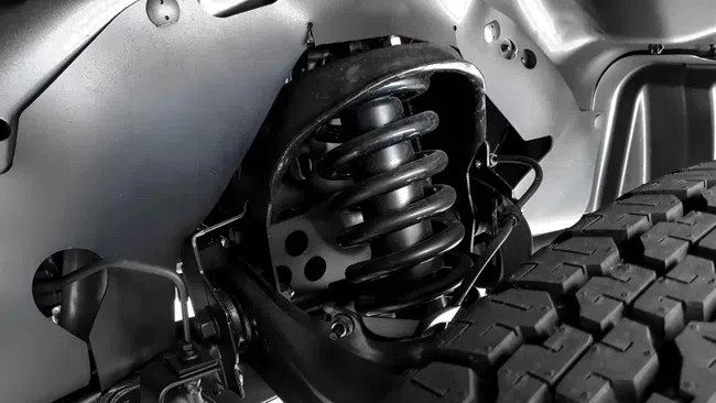 Close-up of a vehicle suspension system showing coil spring and tire tread in black and white.