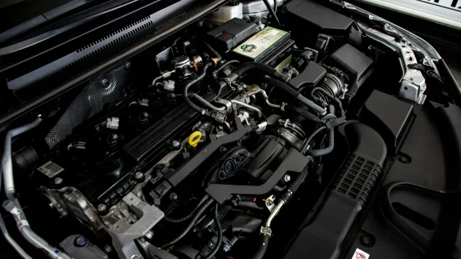 Close-up of a modern car engine showing intricate components, hoses, and electrical wiring under the hood.