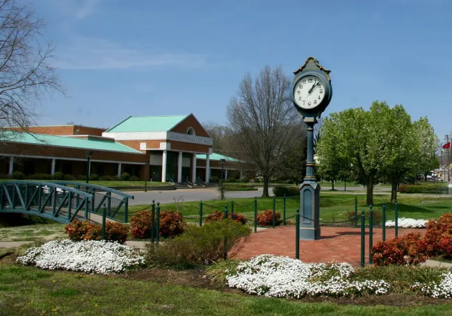 a clock on a post in a park.