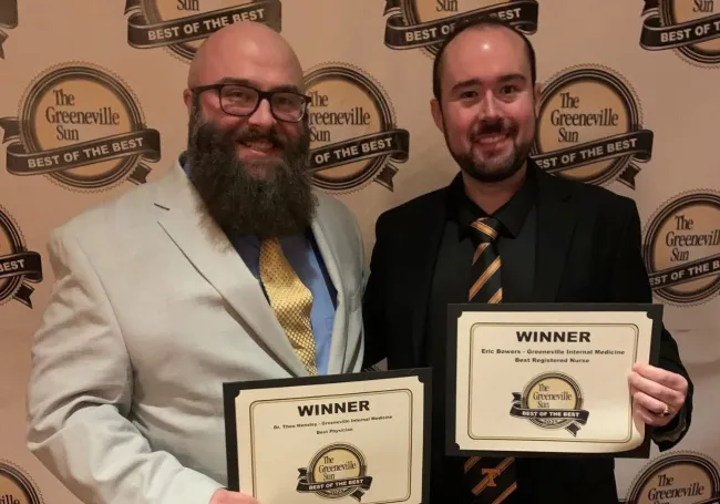 Two men holding Best of the Best certificates from The Greeneville Sun at an award event..