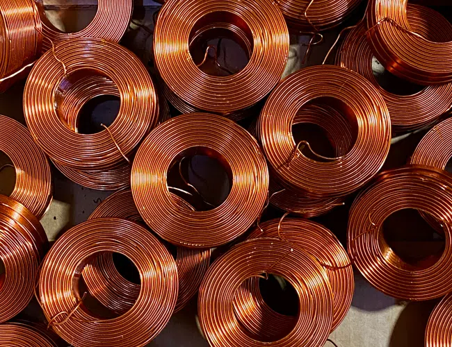 Close-up of tightly coiled copper wires arranged in overlapping circular bundles, showing shiny metallic texture.