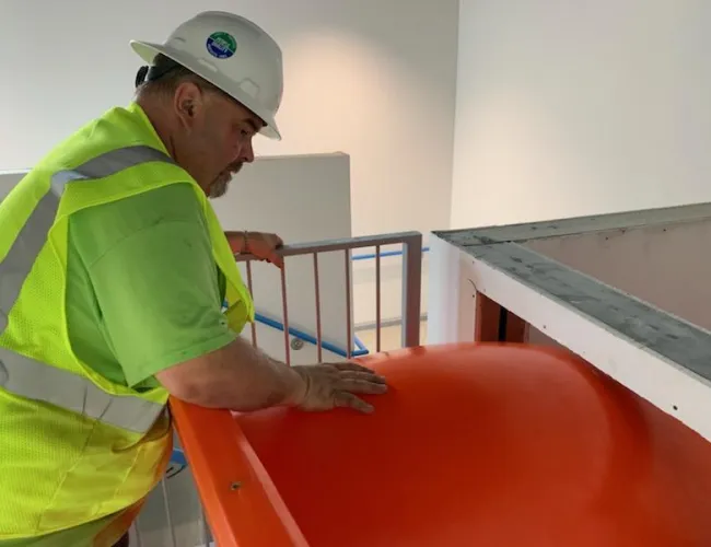 a man in a safety vest working on a red machine