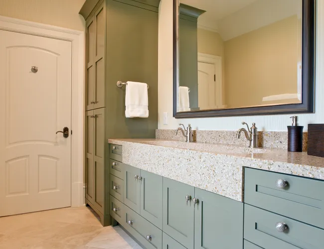 Modern bathroom with large green cabinetry, dual sinks, granite countertop, and a large wall mirror.
