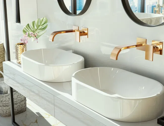 Modern bathroom with white vessel sinks, gold faucets, round mirrors, and stylish decor on vanity counter