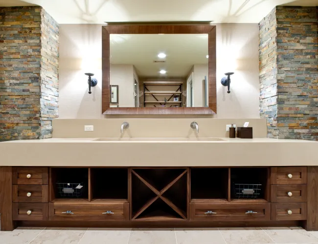 Modern double-sink bathroom vanity with beige countertop, wooden drawers, and stone pillar accents.