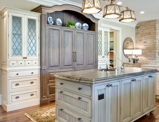 Elegant kitchen with a large wooden island, ornate ceiling light fixture, and hardwood floors with decorative rugs.