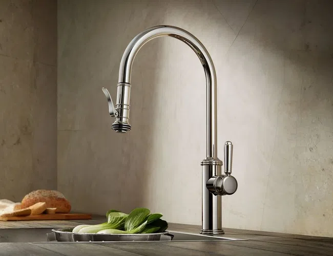 Modern chrome kitchen faucet with lever handle over sink surrounded by fresh vegetables and bread loaf.