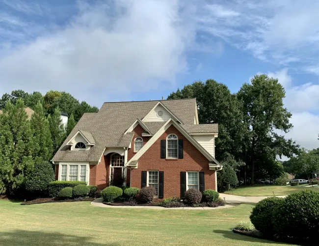 a brick house with a lawn and trees in the front