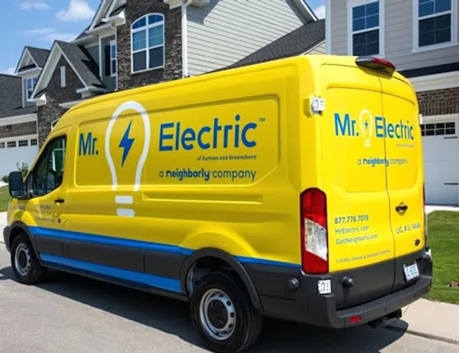 Bright yellow Mr. Electric service van parked in a suburban neighborhood driveway on a sunny day.