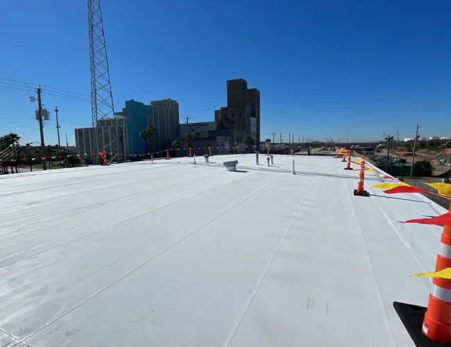 a construction site with a large tarmac road and buildings in the background
