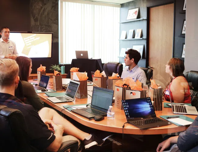 Group of professionals attending a meeting with laptops getting NetSuite Training