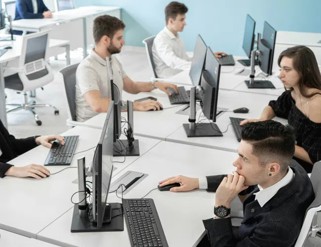 Young professionals working on desktop computers in a modern office with a bright, open layout.