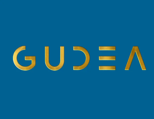 Logo of GUDEA in gold lettering on a solid blue background with modern typography style.