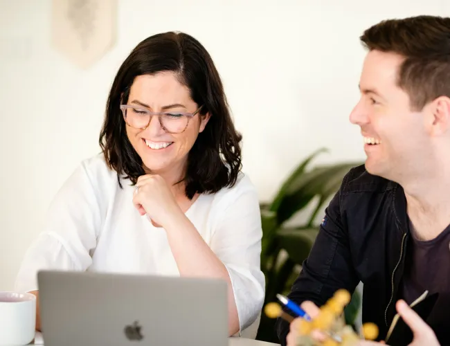 a man and a woman looking at a laptop