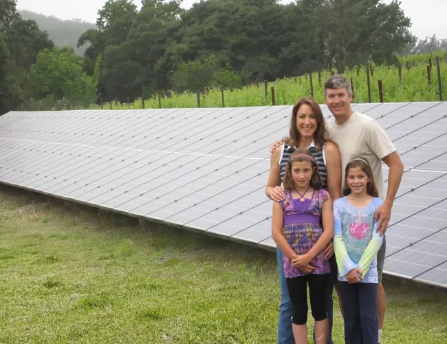 a group of people posing for a photo in front of a solar panel
