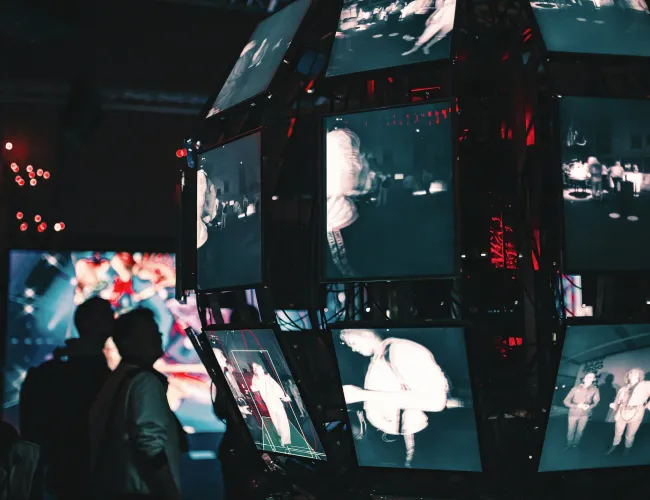 a group of people looking at a large screen with many screens