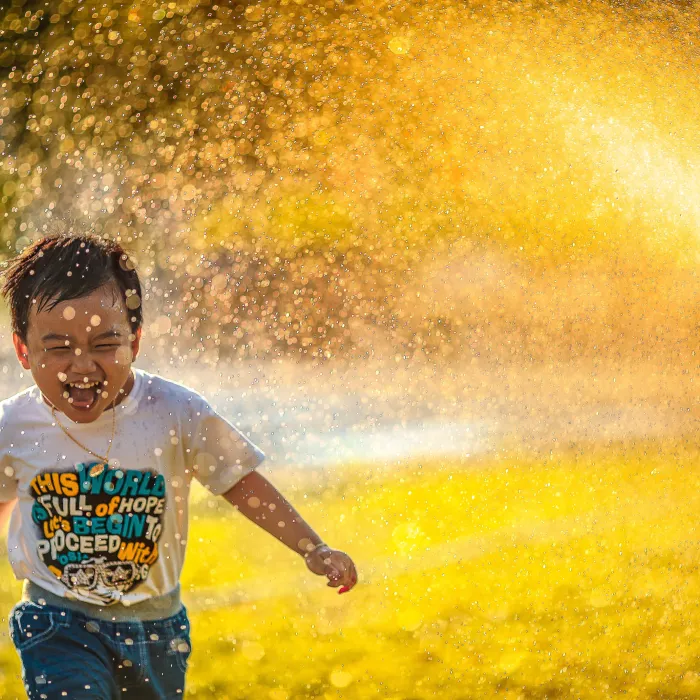 a kid playing in the sprinklers