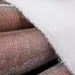 Close-up of soft, textured fabric with a shiny metallic brown surface partially covered by white fuzzy material.