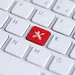 White keyboard with a single red key featuring wrench and screwdriver icons for tools and settings.