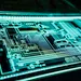Close-up of illuminated electronic circuit board with intricate pathways and components on a dark background