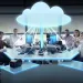 Team of professionals at office desks connected to a glowing cloud symbolizing cloud computing technology.
